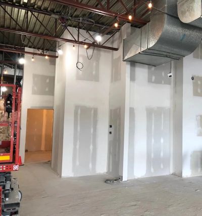 Interior of a building under construction with drywall and exposed ceiling ducts.