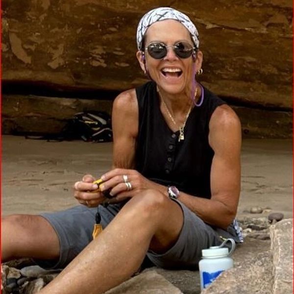 Smiling woman sitting outdoors with water bottle.