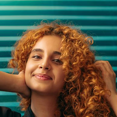 Image of woman with red hair with awesome curls after recieving cut and hair therapy at Studio Joi.