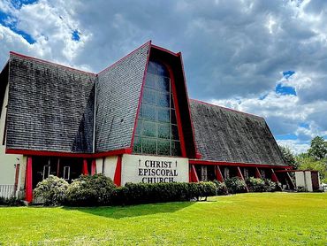Modern Christ Episcopal Church building with large stained glass window and sharp roof design.