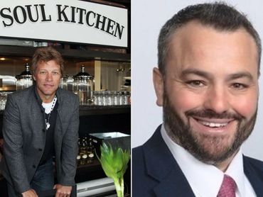 Man standing in front of a Soul Kitchen sign in a casual outfit.