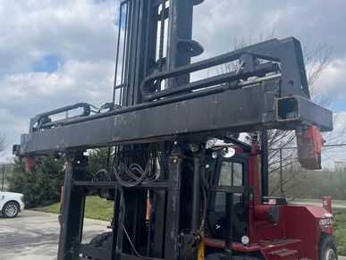 Large industrial forklift with extended lifting arms outdoors.