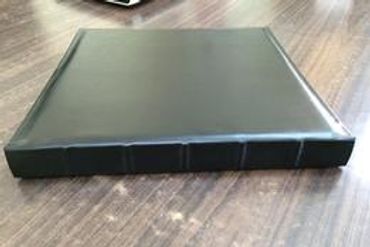 Closed dark green binder on a wooden surface.