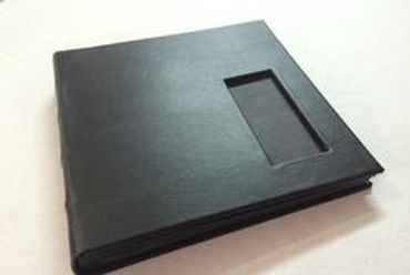 Closed black leather-bound book with a rectangular cutout on the cover.
