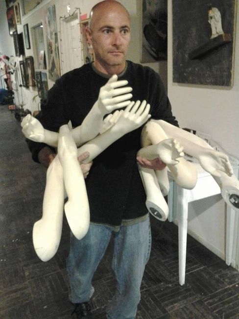 Bret J. Barrett, artist, walking down hallway carrying dismantled limbs in preparation for showcase 