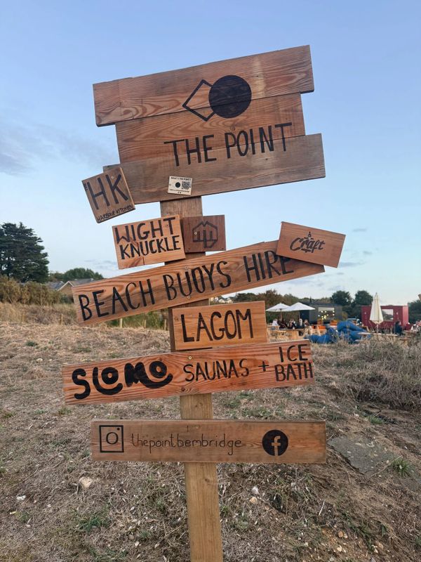 Wooden signpost with various business names and services in a natural setting.