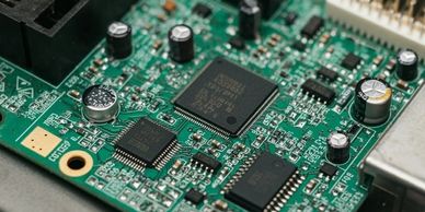 Close-up of a green electronic circuit board with chips and capacitors.