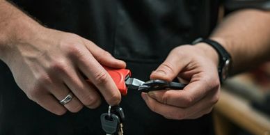 Person holding keys and a key cutting tool, preparing to duplicate a key.