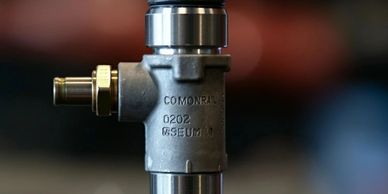 Close-up of a common rail fuel injector with engraved markings.