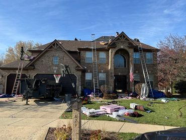 Workers are repairing the roof of a large brick house on a clear day.