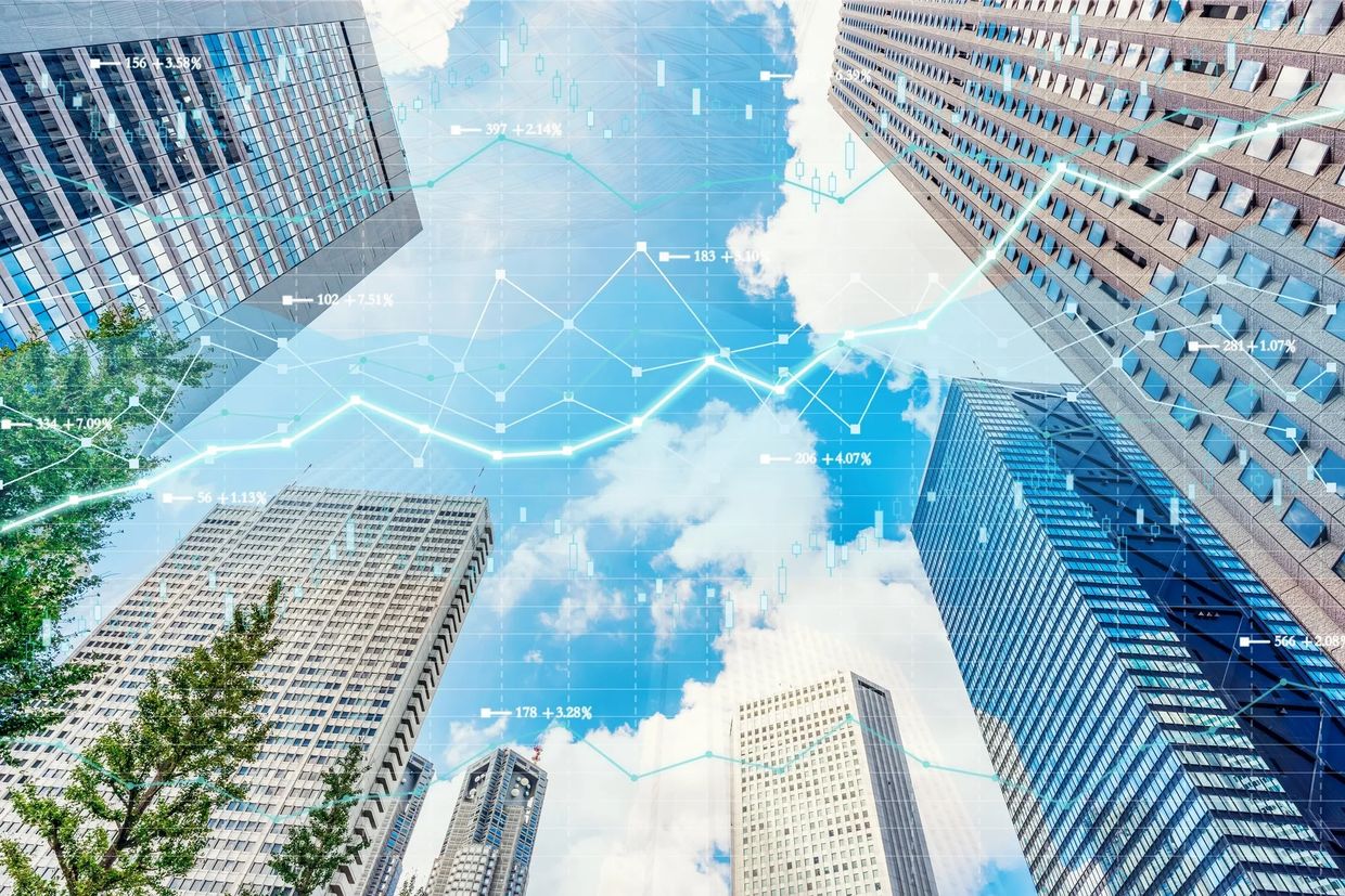 Skyscrapers with financial data overlay against blue sky.