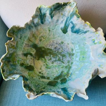 A ceramic bowl with ruffled edges and a green-blue glaze pattern.