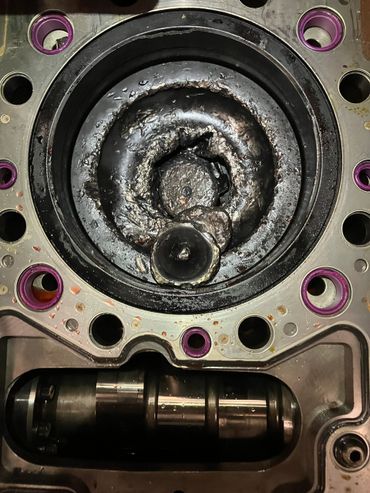 Damaged engine cylinder head with severe carbon buildup and wear.
