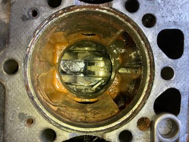 Close-up view inside a rusty engine cylinder with visible piston and valves.