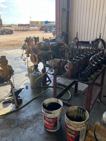 Industrial workshop with engine parts and oil buckets inside a garage.
