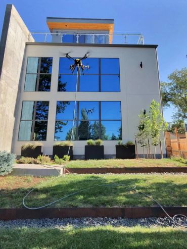 Drone power washing a modern three-story home in Denver