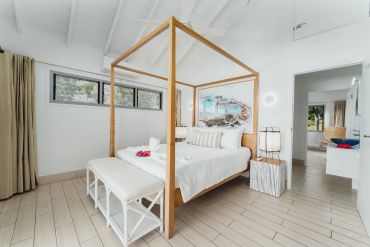 Bright modern bedroom with wooden four-poster bed.