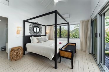 Modern bedroom with a black four-poster bed and natural light.