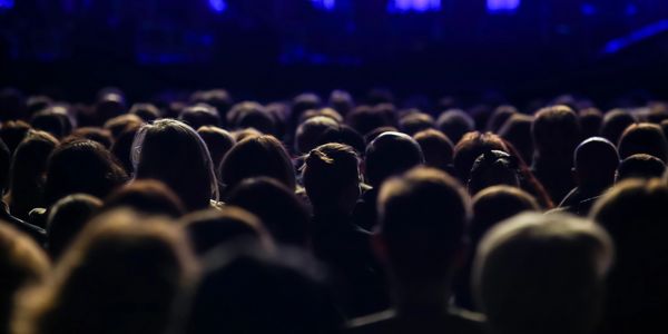 Crowd of people at a nighttime event with blue lighting.