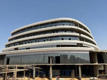 Modern multi-story building under construction with glass facade.