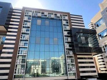 Modern glass-paneled building with decorative white framework.