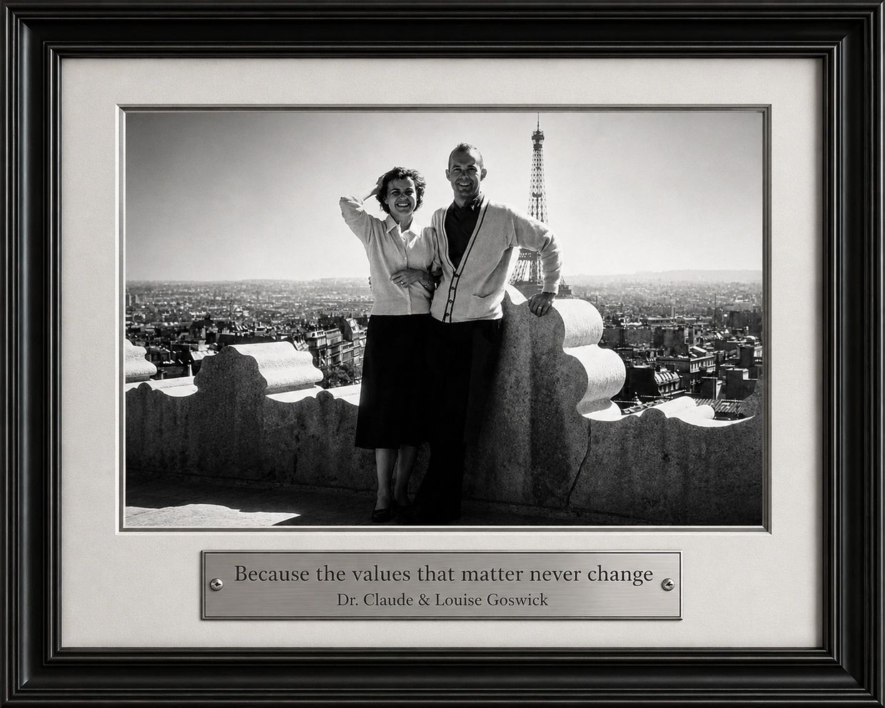 Black and white photo of a couple near Eiffel Tower with a plaque.