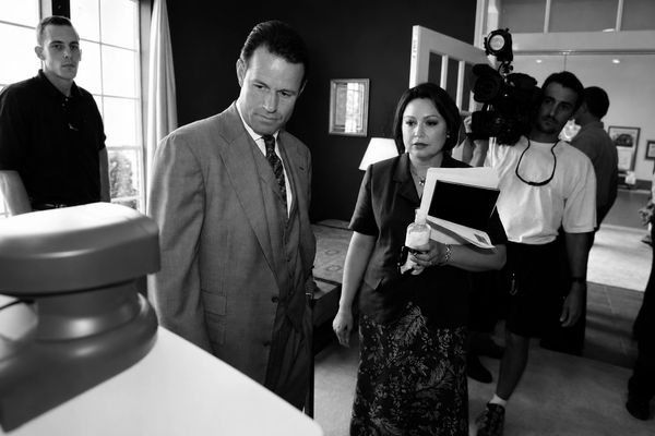 People examining an object in a room with a video camera operator.