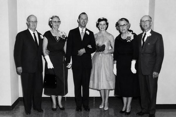 Vintage black-and-white wedding group photo with six people.