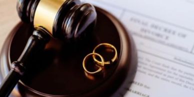 Judge gavel with two wedding rings on legal papers.
