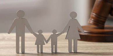 Paper cutout family with a judge's gavel in the background.