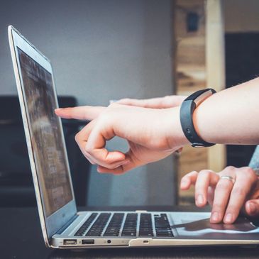 A person points to their laptop screen.