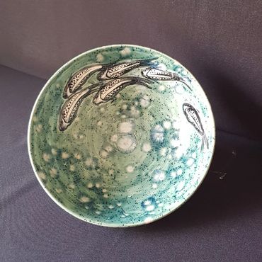 Bowl with fishes swimming on blue background