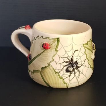 Spider and ladybird painted on top of leaves on mug