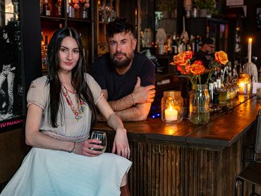 Bar manager and owner seated at the counter with drinks and candles