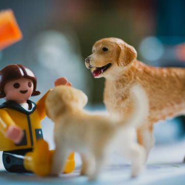 Toy figure with two dog figurines in playful scene.