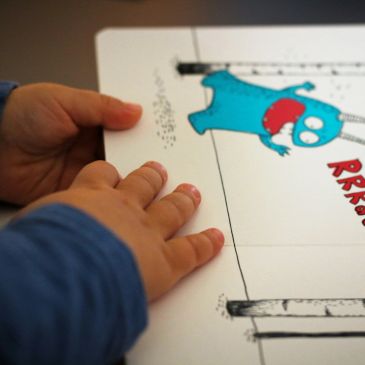Child's hands touching a colorful illustrated book.