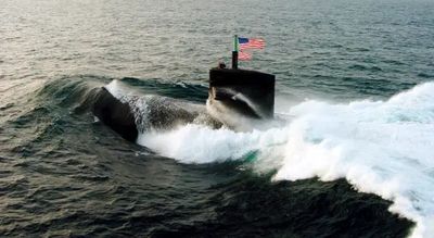 Submarine surfacing in ocean with American flag.