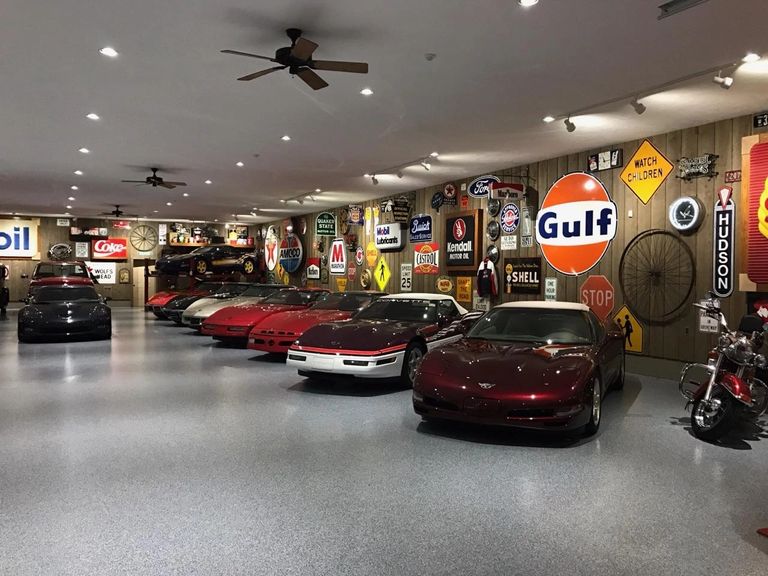 Large garage with a newly epoxy-coated floor, 10 plus sports cars and signage on the walls.