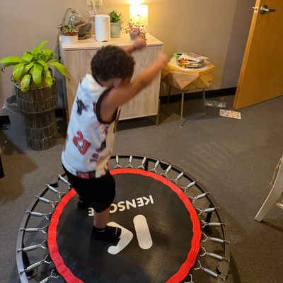 Child jumping on a small indoor trampoline in a cozy room.