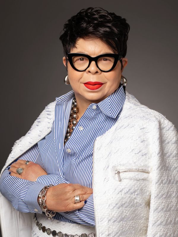 Wialillian Howard in a professional portrait wearing bold glasses and a white jacket.