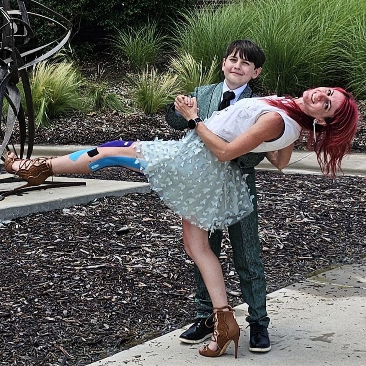 Young boy and woman posing with dance dip outdoors.