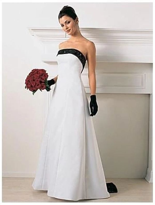 Elegant woman in a white strapless gown holding a red rose bouquet.