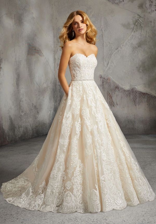 Elegant strapless wedding dress with intricate lace detailing and a flowing train.
