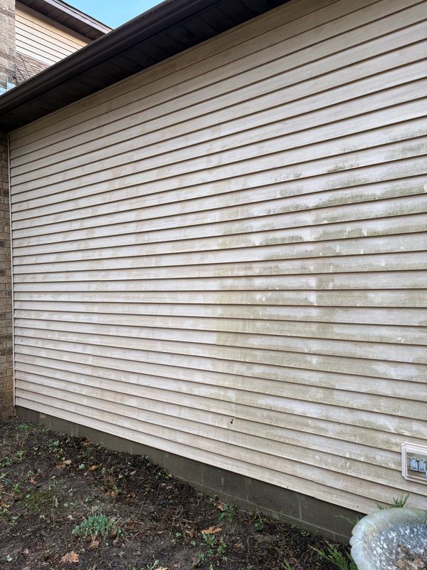Partially cleaned siding showing a stark contrast on a house exterior.