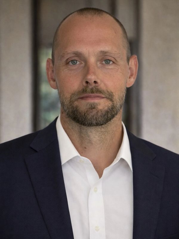 Portrait of a man in a suit with a beard and blue eyes.