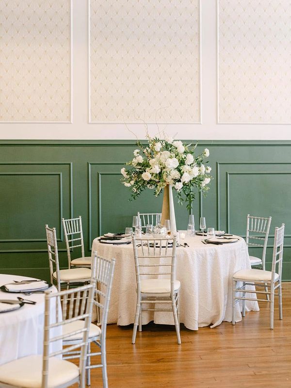 Elegant round table with floral centerpiece in a green and white room.