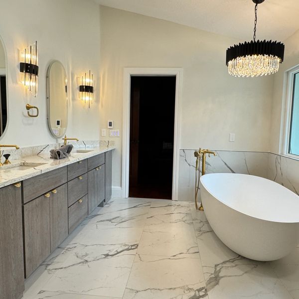 Modern bathroom with marble floor, freestanding bathtub, and elegant lighting fixtures.