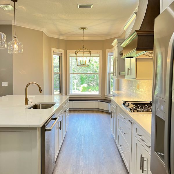 Bright modern kitchen with white cabinets and large bay window seating area.