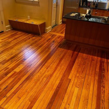 Polished wooden floor in a kitchen with warm lighting.