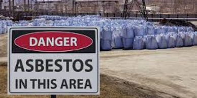 A sign that says, "Asbestos in this area" with bails of asbestos in the background.